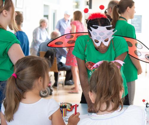 a lady wearing a lady bird costume is talking to some children